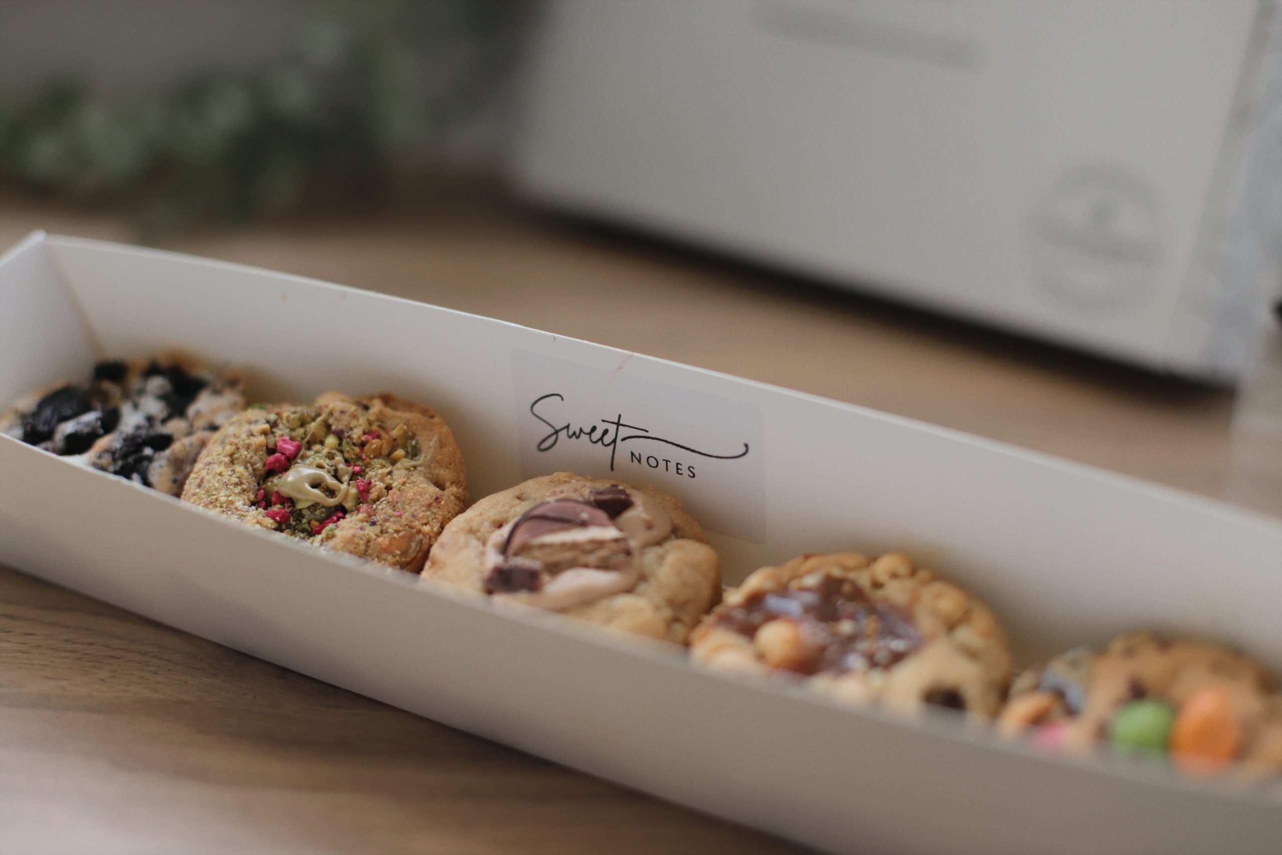 Coffret Sweet Notes avec assortiment de cookies artisanaux variés, vu en gros plan sur la boîte blanche au logo de la marque.